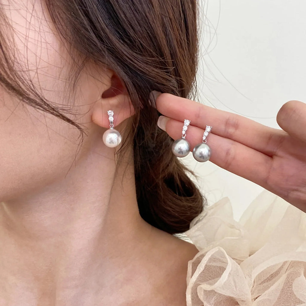 Selunyra white diamond pearl drop earring worn with alternate gray pair shown