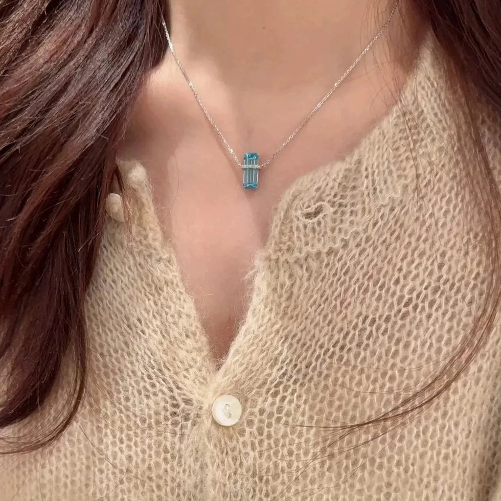 Selunyra Emerald Cut Blue D Necklace with beige knit top