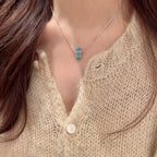 Selunyra Emerald Cut Blue D Necklace with beige knit top