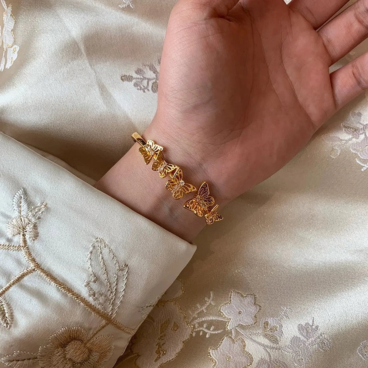 Selunyra Gold Butterfly Bracelet worn with embroidered silk