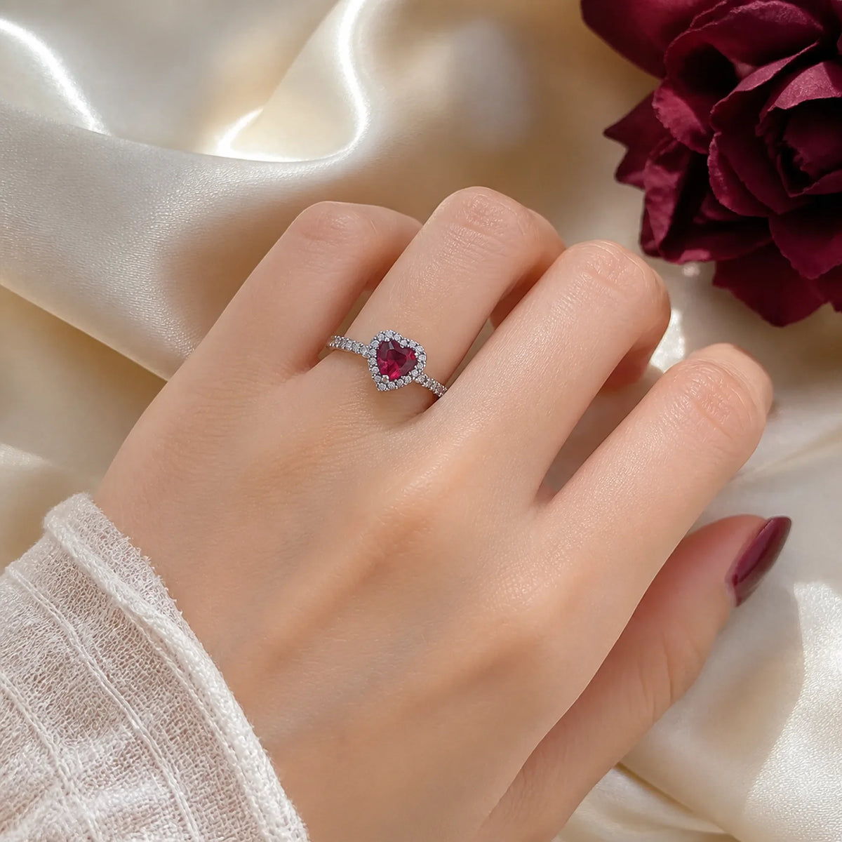 Selunyra red heart halo ring worn on cream satin