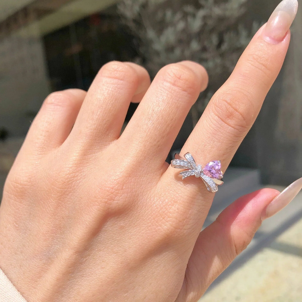 Selunyra pink heart and bow ring worn close-up