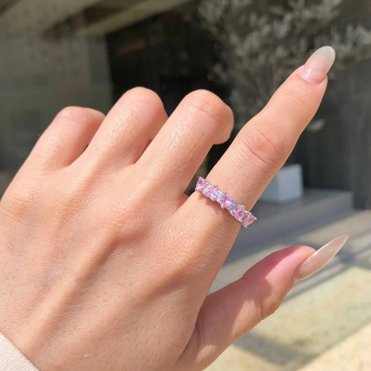 Selunyra pink hearts row ring worn close-up